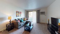 Located at 1815 Raleigh Ave in Kendallville, Indiana, this single-floor residence offers a well-organized and functional layout across its living spaces. The living room is carpeted and filled with natural light, highlighted by a sliding glass door with vertical blinds that opens to an outdoor view, creating a welcoming and open atmosphere. A wall-mounted air conditioning unit provides climate control for added comfort.

Adjacent to the living room, the dining area features a ceiling fan with light fixture and connects seamlessly to the kitchen, which is designed in a galley style with white cabinetry trimmed in wood tone, dark hardwood-style flooring, a double-basin stainless steel sink, dishwasher, and full-size refrigerator — offering practical functionality in a compact footprint.

The unit includes two bedrooms, each carpeted and equipped with closet space and windows that let in natural light. The primary bedroom features a ceiling fan, multiple windows, and generous floor space, while the second bedroom also includes a closet and a baseboard heater beneath its window.

The bathroom is finished with hardwood-style flooring, a wide vanity with a large mirror, open wall shelving, and a shower-tub combination. Throughout the residence, a consistent neutral palette and carpeted living areas contribute to a comfortable, livable ambiance.