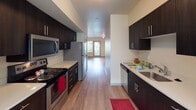 Located at 18025 SE 272nd St in Covington, Washington, this ground-floor unit offers a well-designed, single-level layout that balances comfort and functionality. The living room serves as the heart of the home, featuring warm hardwood-style flooring, a built-in fireplace with a clean white mantel, and a sliding glass door that opens to a private patio, allowing natural light and outdoor views to flow freely into the space. Track lighting overhead completes the inviting atmosphere.

The galley-style kitchen is thoughtfully appointed with dark espresso cabinetry, stainless steel appliances including an electric range, microwave, refrigerator, and dishwasher, along with light countertops and a double sink. The layout provides generous counter and storage space along both walls, opening toward a bright dining or flex area.

The bedrooms are carpeted for comfort and feature windows with outdoor views, offering a quiet and restful setting. An additional room with hardwood-style flooring provides flexible use as a bedroom or office. The bathroom includes a full tub-and-shower combination, a dark wood vanity with a white sink, and hardwood-style flooring, maintaining a consistent and clean aesthetic throughout the unit.