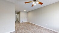 Located at 1738 Hanover St in Murfreesboro, Tennessee, this single-floor one-bedroom, one-bathroom home offers an efficient and well-organized layout. The living room serves as the welcoming centerpiece of the home, featuring light wood-look plank flooring, neutral gray walls, clean white baseboards, and a ceiling fan with integrated lighting. Natural light filters in through a window, brightening the open feel of the space, while a textured ceiling adds a classic touch. The entry door opens directly into this main living area, reinforcing the straightforward and accessible flow of the floor plan. The bedroom is a comfortable retreat, finished with plush wall-to-wall carpeting, soft neutral wall tones, and its own ceiling fan with a window that offers a view of the surrounding greenery. A paneled white door completes the room's clean aesthetic. The bathroom is practical and neatly appointed, featuring wood-look tile flooring, a warm oak vanity with white countertop, a wall-mounted mirror with overhead lighting, and a full bathtub. Throughout the home, a consistent neutral color palette and functional finishes create a cohesive, move-in-ready environment well-suited for comfortable everyday living.