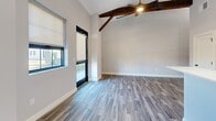 Located at 7 Stickney Ave in Concord, NH, this thoughtfully designed two-bedroom, one-bathroom unit combines modern finishes with distinctive architectural character. The open living and kitchen area immediately impresses with soaring vaulted ceilings, exposed rustic wood beams, and wood-look luxury vinyl plank flooring throughout, creating a warm yet contemporary ambiance. Large black-framed windows and a glass door flood the space with natural light while offering outdoor views.

The kitchen is well-appointed with slate-blue shaker cabinetry, quartz countertops, a white subway tile backsplash, and a full suite of stainless steel appliances, including a refrigerator, range, and microwave. A peninsula with pendant lighting adds both counter space and a casual dining option.

Both bedrooms feature soft carpeting, neutral walls, and built-in closets with shelving. The generously sized primary bedroom includes a window that brings in additional natural light. The full bathroom is finished with wood-look tile flooring, a gray vanity with a white countertop, matte black fixtures, a tub-shower combination, and the added convenience of an in-unit stacked washer and dryer.
