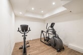 Located at 5801 W Pico Blvd in Los Angeles, this modern fitness facility offers a thoughtfully designed workout space spread across a single floor. The gym is divided into distinct functional zones, each tailored to a specific type of exercise, and is finished with a clean, contemporary aesthetic throughout.

The cardio area features multiple Vision treadmills positioned along textured wood-paneled accent walls, complemented by recessed and linear LED lighting that creates a bright, energizing atmosphere. Durable rubber flooring covers the main workout areas, providing both safety and comfort underfoot, while a separate section with wood-look flooring houses an elliptical trainer for low-impact cardio options.

The strength training zone is outfitted with SportsArt cable machines and a multi-function weight system, offering a comprehensive range of resistance exercises. Additional equipment, including a rowing machine and a cable/pulley station, rounds out the selection for a full-body workout experience.

The facility's interior is characterized by crisp white walls, coffered ceiling details, and sleek linear LED strip lighting that runs across the ceiling, lending the space a polished, upscale feel. The layout flows efficiently between zones, making navigation intuitive. A dedicated entry door and climate control systems ensure comfort year-round, making this gym a well-appointed and functional fitness destination.
