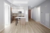 Located on the 31st floor of 20 George St in downtown Hamilton, this thoughtfully designed two-bedroom, two-bathroom unit offers a bright and modern living experience. Light hardwood-style flooring runs consistently throughout, complementing the neutral warm-grey and white palette that creates a clean, cohesive aesthetic.

The open-concept kitchen is well-appointed with two-tone cabinetry — combining white upper cabinets with wood-finish lower units — stainless steel appliances including a refrigerator, microwave, and stove, a subway tile backsplash, and a peninsula with a white quartz countertop that doubles as a breakfast bar. The adjoining living area benefits from natural light streaming through large floor-to-ceiling windows with roller blinds.

Both bedrooms are generously proportioned with large windows framing impressive elevated views of the Hamilton skyline and surrounding cityscape, filling each room with abundant natural light. The primary bedroom is a comfortable size, offering ample space for furnishings.

The two bathrooms are finished in a consistent modern style. One features a soaker tub and shower combination with chrome fixtures and a wood-finish vanity with white quartz countertop, while the second is a larger ensuite-style bathroom with an extended vanity, dual mirrors, and a glass-enclosed shower. A hallway connects all rooms efficiently, completing this well-organized and stylish unit.