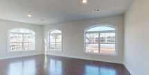 Located at 339 W Broad St in Westfield, NJ, this single-floor space offers a thoughtfully designed layout with high-quality finishes throughout. The open living area is a standout feature, showcasing rich, dark hardwood flooring that extends seamlessly across the space. Expansive arched and picture windows line the walls, flooding the interior with abundant natural light while offering views of the surrounding neighborhood. Recessed lighting complements the bright, airy atmosphere created by the neutral wall tones and clean white trim.

The kitchen is well-equipped for functionality, featuring stainless steel appliances including a gas range, over-the-range microwave, and full-size refrigerator. White shaker-style cabinetry pairs with gray countertops and a mosaic tile backsplash, while an integrated peninsula provides additional prep and storage space. Light tile flooring in the kitchen transitions to hardwood in the adjoining areas.

The bathrooms are finished with clean, modern details. One bathroom features a sliding glass-enclosed shower with marble-look tile surround and matching floor tile, while additional bathrooms include white vanities with dark countertops and large mirrors. Hallways connect the private rooms, which offer hardwood floors, neutral walls, and natural light from well-placed windows.