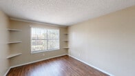 Located at 3241 Bonnie Dr in Fort Worth, TX, this one-bedroom, one-bathroom unit offers a practical and efficient single-floor layout. Wood-look flooring runs throughout the main living areas, lending warmth and continuity to the space. The open-concept living, dining, and kitchen area forms the heart of the unit, providing a versatile space for everyday living and entertaining. The kitchen is equipped with warm-toned cabinetry, a stainless steel refrigerator, a coil-top range, and a dishwasher, complemented by a tile backsplash and light granite-style countertops. The bedroom features built-in corner shelving flanking a window that allows natural light and outdoor views, along with additional closet space — with three closets total throughout the unit offering generous storage. A ceiling fan keeps the space comfortable. Neutral, warm beige tones on the walls are consistent throughout, creating a cohesive and calming ambiance. The bathroom includes a full tub-shower combination with white tile surround. Textured ceilings are present throughout the unit, adding a classic residential character to the overall design.