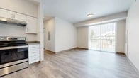 This modern single-floor unit at 400 Schwitzer Plaza Dr in Ponderay, Idaho offers a clean, contemporary design throughout. Light-toned luxury vinyl plank flooring runs consistently across all rooms, complementing the bright, neutral color palette of white walls and warm wood-tone baseboards.

The kitchen is well-appointed with white shaker-style cabinetry, dark countertops, and stainless steel appliances including a range with overhead ventilation. Ample storage is provided by both upper and lower cabinets, making the kitchen both functional and visually appealing.

The open living area is generously proportioned, filled with natural light from a large sliding glass door fitted with vertical blinds that leads to an outdoor balcony, offering views of the surrounding neighborhood. The space feels bright and airy, with recessed and flush-mount lighting throughout.

Multiple bedrooms provide comfortable, well-lit spaces, each featuring windows with horizontal blinds that allow for natural light and outdoor views. The rooms are clean and versatile in layout.

Two bathrooms serve the unit — one featuring a full soaking tub and shower combination with white surround, and another offering a single vanity with dark countertop, white cabinetry, and a mirror. Both bathrooms continue the consistent use of wood-look flooring and crisp white finishes found throughout the unit.
