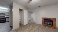 This single-floor residence offers a practical and comfortable layout with a variety of functional spaces. The main living area is carpeted and features a classic brick fireplace as a focal point, adding warmth and character to the room. A ceiling fan overhead aids in climate comfort, while a built-in shelving closet provides convenient storage. A hallway connects the living area to the rest of the home, maintaining a smooth flow between spaces. Natural light enters through a window fitted with horizontal blinds, brightening the entry area, which transitions from carpet to durable wood-look vinyl flooring near the front door. The kitchen is well-equipped with gray cabinetry, dark speckled countertops, black appliances including a range and dishwasher, a double-basin stainless steel sink, and wood-look vinyl flooring, creating a cohesive and functional cooking space. The bedrooms are carpeted and finished with textured walls and ceilings, offering quiet, comfortable retreats. The bathroom includes a dark granite-style vanity countertop with a single sink, and a separate tiled tub and shower combo with wood-look flooring. Throughout, textured ceilings and neutral tones contribute to a clean, understated aesthetic.