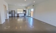 This contemporary 2-bedroom, 3-bathroom townhouse in Los Angeles offers 1,160 square feet of thoughtfully designed living space across two floors. The ground floor (550 sq ft) features a combined kitchen and living area with polished concrete floors and recessed lighting. The kitchen is outfitted with sleek white cabinetry, stainless steel appliances including a French-door refrigerator, dishwasher, microwave, and range, plus a window above the sink for natural light. A modern staircase with wood treads and metal railings connects the floors. The upper level (610 sq ft) hosts both bedrooms, including a 200 sq ft primary bedroom with wide-plank hardwood floors, bright windows offering neighborhood views, and access to a well-appointed bathroom featuring dual vessel sinks, a large vanity mirror, and a glass-enclosed shower with tile surround. The second bedroom also features hardwood floors and ample natural light. A standout feature is the expansive private rooftop deck, providing open-air views of the Los Angeles skyline and surrounding greenery — ideal for outdoor entertaining. Clean white walls and a minimalist aesthetic define the overall ambiance of this modern urban residence.