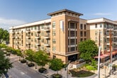This single-floor unit offers a thoughtfully designed layout that balances functionality and comfort. The kitchen is a standout feature, showcasing rich dark espresso cabinetry that extends to the ceiling, white tile backsplash, and light-toned countertops that provide strong visual contrast. Stainless steel appliances — including a dishwasher, over-the-range microwave, and electric range — give the kitchen a polished, modern feel, while dark hardwood-style flooring ties the space together seamlessly. A granite-accented island or peninsula adds additional prep and serving space.

The living area is inviting and versatile, with warm neutral walls, the same dark hardwood-style flooring, and ample room for a full sectional sofa and coffee table. Wall art and soft lighting contribute to a relaxed yet stylish ambiance.

The bedroom features plush carpeting for added comfort, warm beige tones on the walls, and a unique skylight detail that introduces natural light from above, creating an airy feel.

The bathroom is neatly appointed with dark cabinetry echoing the kitchen's design language, a single-basin vanity with a large mirror, bright overhead lighting, and accessibility-friendly grab bars — combining practicality with clean, consistent style throughout the unit.