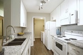 Located at 1635 Pirkle Rd in Norcross, Georgia, this single-floor residence offers a thoughtfully designed layout with a cohesive, eclectic aesthetic throughout. The galley-style kitchen is outfitted with crisp white cabinetry, granite-look countertops, a subway tile backsplash, and wood-look flooring, with white appliances and a deep undermount sink lending a clean, functional character to the space. A pass-through connects the kitchen to the rest of the home with ease. The living room is warm and inviting, anchored by a ceiling fan and slider doors that open to an outdoor balcony, allowing natural light to filter through patterned drapes. A mid-century modern credenza and bold decorative mirror add personality to the space. The adjacent dining area features wood-look flooring, track lighting, and a cozy round table setup beneath a gallery-style wall arrangement. Two bedrooms each carry their own distinct character — one dressed in a vivid teal accent wall with a gold-toned headboard and plush carpet, and the other showcasing a bold mustard yellow accent wall with earthy wood furnishings and soft carpet underfoot. The bathrooms feature tiled tub-shower combinations and wood-look flooring, maintaining the home's clean, updated aesthetic throughout.