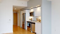 Located in the heart of Halifax, NS, this two-bedroom, one-bathroom unit at 5121 Bishop St offers a thoughtfully designed layout with a clean, contemporary aesthetic throughout. Light hardwood flooring flows seamlessly across the entire space, complementing the crisp white walls and creating a bright, cohesive atmosphere.

The open-concept kitchen and living area serves as the heart of the unit. The kitchen is well-appointed with sleek white cabinetry extending to the ceiling for ample storage, a white subway tile backsplash, light stone countertops, and a full suite of stainless steel appliances including a French door refrigerator, electric range, built-in microwave, and dishwasher.

Floor-to-ceiling windows in the living area and primary bedroom flood the space with natural light and frame sweeping views of Halifax Harbour and the surrounding cityscape — a true standout feature of this elevated unit. A structural column adds an architectural character to the corner window configuration.

The primary bedroom is a comfortable retreat with large harbour-facing windows, while the second bedroom offers a built-in closet and clean, minimal finishes. The full bathroom features large-format marble-look tile flooring, a white vanity, and a tiled tub-shower combination, maintaining the unit's modern and polished design language throughout.