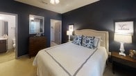 Located at 230 City Green Way in Chattanooga, Tennessee, this single-floor residence combines contemporary design with functional living. A welcoming hallway finished with wood-look flooring, framed wall art, and pendant lighting sets an elegant tone as it connects the home's key spaces.

The kitchen is a standout feature, offering rich dark-stained cabinetry, light-toned countertops, and a full suite of black appliances including an electric range, over-the-range microwave, and refrigerator. Generous counter space and ample upper and lower cabinetry provide excellent storage and workspace. A doorway from the kitchen leads directly to an in-unit laundry room, adding notable everyday convenience.

Adjacent to the kitchen, the dining area accommodates a round table beneath a large drum pendant light, creating a cozy and intimate setting for meals.

The living room features bold, dark accent walls that contrast with neutral furnishings and a patterned area rug, lending the space a sophisticated, modern character. Natural light filters in through sliding glass doors that open to an outdoor balcony.

Two bedrooms offer distinct personalities: one features deep navy walls and plush carpeting for a dramatic, restful retreat, while the second presents a softer, neutral palette with warm-toned accents. Both rooms include closets and ceiling fixtures.

The bathroom maintains the home's consistent aesthetic with dark cabinetry, a wide vanity mirror, and wood-look tile flooring.