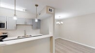 Located at 2600 Arroyo Ave in Dallas, TX 75219, this two-story 1-bedroom, 1-bathroom home is thoughtfully designed across two equally sized floors. The main level features an open-concept kitchen and living area finished with light wood-style flooring and a neutral color palette. The kitchen is a standout, showcasing gray cabinetry, a white quartz countertop with a breakfast bar, a geometric hexagonal tile backsplash, stainless steel appliances, and pendant lighting that adds a modern touch. The living area flows naturally from the kitchen and is illuminated by a contemporary chandelier. A staircase connects the two floors, leading to the upper level where the spacious primary bedroom resides. The bedroom features plush carpeting, a ceiling fan, natural light from blinds-covered windows, a built-in shelf or desk nook, and direct access to the full bathroom. The bathroom is clean and functional, offering a tub-shower combination with brushed nickel fixtures and white tile surround. Hallways on both floors provide practical circulation throughout the home. The overall aesthetic is modern and cohesive, with warm neutrals and quality finishes creating a comfortable, move-in-ready living environment.