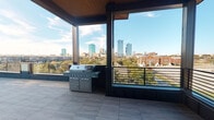 Located at 319–347 Nichols St in Fort Worth, Texas, this amenity-focused space offers a compelling combination of fitness facilities and outdoor entertaining areas designed to serve an elevated urban lifestyle.

The fitness center is divided into two distinct zones connected by glass-panel doors. The main workout area features bold red accent walls, ceiling fans, recessed lighting, and floor-to-ceiling mirrors that visually expand the space. It is equipped with a multi-station cable machine, elliptical trainers, treadmills, cycling equipment, stability balls, yoga mats, and free weights, providing a comprehensive range of cardio and strength training options. A mounted flat-screen television and natural light from multiple windows with blinds add functionality and comfort. An adjoining studio room with wood-style flooring, a chandelier, and mirrored walls offers a versatile space suited for yoga, stretching, or group classes.

The covered outdoor terrace is a standout feature, showcasing large-format tile flooring, a dark steel-framed structure with a wood-paneled ceiling, and a built-in gas grill. Expansive glass panels and open railings frame sweeping, unobstructed views of the Fort Worth downtown skyline, making it an ideal space for outdoor gatherings.
