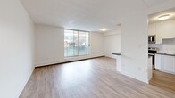 Located at 1189 Talwood Court in Peterborough, Ontario, this one-bedroom, one-bathroom unit offers a thoughtfully designed open-concept layout finished with light hardwood-style flooring throughout. The combined living, dining, and kitchen area forms the heart of the unit, bathed in natural light from large sliding glass doors that open to an outdoor balcony with views of the surrounding neighbourhood. A half-wall peninsula with a dark countertop provides a natural division between the living and kitchen areas while maintaining an open feel. The kitchen is well-appointed with white shaker-style cabinetry, grey stone countertops, a classic white subway tile backsplash, and stainless steel appliances including an electric range, over-the-range microwave, and refrigerator. The bedroom is a comfortable, private space featuring its own large sliding glass door for natural light and outdoor access. Baseboard heating runs along the perimeter of multiple rooms, ensuring efficient warmth throughout. The bathroom is finished with a full-sized soaker tub and shower, surrounded by crisp white subway tile. Clean white walls and a textured ceiling complete the bright, modern aesthetic of this well-maintained unit.