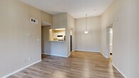 This single-floor residence offers a practical and well-organized layout across four bedrooms, two bathrooms, a living room, dining room, and kitchen. The open-plan living and dining area is immediately notable for its vaulted ceiling, which lends a sense of spaciousness beyond the unit's compact footprint. Light hardwood-style flooring extends throughout these shared spaces, complemented by neutral beige walls that create a clean, cohesive aesthetic. A pendant light fixture anchors the dining area, which connects directly to the kitchen via a pass-through opening, promoting an open and communicative flow between spaces.

The kitchen is galley-style, featuring white cabinetry, a double-basin stainless steel sink, light countertops, a dishwasher, and a full-size refrigerator. A closet accessible from the kitchen provides additional storage.

The bedrooms present a quieter, more private atmosphere. The primary bedroom offers a comfortable footprint with hardwood-style flooring and a window admitting natural light, while additional bedrooms feature soft carpeting and textured ceilings. The two bathrooms include tub-shower combinations with white tile surrounds and chrome fixtures, maintaining a consistent, functional design throughout the home.