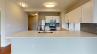 Located at 8 Kimball Ct in Woburn, Massachusetts, this well-appointed single-floor residence offers a thoughtfully designed layout with contemporary finishes throughout. The open-concept kitchen is a standout feature, showcasing crisp white cabinetry, a subway tile backsplash, stainless steel appliances including a refrigerator, range, microwave, and dishwasher, and a large white quartz countertop peninsula with an undermount sink — ideal for both cooking and casual dining. Hardwood flooring runs throughout the main living areas, adding warmth and continuity to the space. The expansive living area is bathed in natural light through a generous wraparound bank of windows offering pleasant outdoor views of the surrounding greenery and neighborhood. Bedrooms are carpeted for comfort and each features large windows that continue the theme of abundant natural light. The unit includes two bathrooms: one with a walk-in glass-enclosed shower and wood-look flooring, and a second full bath with a soaking tub and shower combination, vanity with ample storage, and a large mirror. A dedicated in-unit laundry closet with full-size washer and dryer adds everyday convenience. The entry foyer provides a welcoming transition into the home, completing this clean, modern, and functional living space.