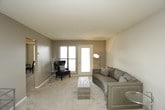 This single-floor residence offers a thoughtfully arranged layout with a range of functional spaces designed for comfortable everyday living. The living room features plush carpeting, neutral-toned walls, and a sliding door that allows natural light to fill the room, creating a bright and welcoming atmosphere. Adjacent to the living area, a dedicated dining space accommodates a full dining set beneath a ceiling fan, providing a practical spot for meals. A secondary room with dual windows and carpeted floors offers versatility as a bedroom or home office. The bedrooms are carpeted and feature warm, neutral wall tones, with windows allowing in natural light. The primary bedroom includes a sliding mirrored closet for ample storage. The kitchen is equipped with dark wood cabinetry, a double sink, electric range, refrigerator, and dishwasher, all set on easy-care laminate flooring. Two bathrooms serve the residence, each featuring classic white tile flooring in a diamond pattern, a toilet, and vanity with sink. One bathroom includes a shower stall, while the other offers a bathtub with shower combination. The overall aesthetic is clean and neutral, offering a move-in-ready environment throughout.