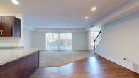 This two-story home offers a thoughtfully designed layout that balances open living spaces with comfortable private quarters. The main level centers around a spacious open-concept living and dining area, where wide sliding glass doors flood the room with natural light and provide views to the outdoors. A mix of hardwood-style flooring and plush carpeting defines distinct zones within the living area, while recessed lighting adds a clean, modern touch overhead. A staircase with a classic wood railing connects the two floors seamlessly.

The kitchen is a functional highlight, featuring rich dark cabinetry, granite countertops, a large peninsula island, and a full suite of black appliances including a refrigerator, range, microwave, and dishwasher. Hardwood-style flooring continues throughout the kitchen, complementing the warm tones of the cabinetry.

Upstairs, the bedrooms are carpeted and bright, with neutral white walls and ample space. Each room offers a quiet, versatile environment, with some featuring windows that bring in natural light. The bathrooms are finished with light tile flooring, dark wood vanities, and classic white subway tile surrounding the soaking tub and shower combinations, creating a clean and timeless aesthetic throughout.