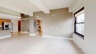 Located in the heart of downtown Detroit at 10 Witherell St, this 2-bedroom, 2-bathroom residence offers a well-designed single-floor layout that balances comfort and urban style. The open-concept living, dining, and kitchen area serves as the centerpiece of the home, with large dark-framed windows flooding the space with natural light and framing striking views of the Detroit skyline. Light-toned tile flooring runs throughout the main living areas, enhancing the bright, airy feel of the space. The kitchen is thoughtfully appointed with warm maple cabinetry, dark granite countertops, stainless steel appliances, a built-in microwave, and a peninsula with a sink — ideal for both cooking and entertaining. Track lighting and pendant fixtures add a modern touch overhead. Both bedrooms feature plush carpet flooring and multiple windows with city views, providing a comfortable retreat. The two bathrooms are clean and functional, with tile flooring and granite-surround tub-shower combinations. Two closets offer ample storage throughout the unit. A dedicated laundry area with stacked LG washer and dryer units and additional cabinetry adds everyday convenience. The entrance leads naturally into the open living space, creating a cohesive and functional flow throughout the home.