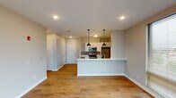 This well-appointed single-floor unit offers a thoughtfully designed open-concept layout that seamlessly connects the kitchen and living area. The kitchen is a standout feature, equipped with stainless steel appliances including a refrigerator, range, microwave, and dishwasher. White shaker-style cabinetry pairs with light quartz countertops and a tile backsplash, while a peninsula with pendant lighting serves as both a functional workspace and a visual divider between the kitchen and the expansive living area. The living space is bathed in natural light courtesy of large windows, and warm wood-look flooring flows consistently throughout the unit, enhancing the cohesive aesthetic.

Two bedrooms each offer ceiling fans with lighting and windows that bring in additional natural light. The unit includes two bathrooms: one features a walk-in shower with chrome fixtures, while the second is appointed with a full soaking tub and shower combination, a white vanity with quartz countertop, and a framed mirror. Neutral-toned walls and recessed lighting throughout contribute to a clean, modern ambiance. The layout, as visible from the dollhouse view, is efficiently organized, with hallways connecting the private spaces to the shared living areas for a practical and comfortable flow.