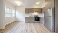 Located at 1416 Lewis Drive in Lakewood, Ohio, this one-bedroom, one-bathroom unit offers a clean, modern aesthetic throughout its efficiently arranged single-floor layout. Light wood-tone luxury vinyl plank flooring runs continuously across all rooms, creating a cohesive and airy feel.

The living room is a welcoming, well-lit space featuring multiple windows with blinds that allow abundant natural light, a ceiling fan with integrated lighting, and baseboard heating. The open sightlines and neutral wall tones make the space feel open and versatile.

The kitchen is outfitted with contemporary flat-front cabinetry in a warm wood-grain finish, stainless steel appliances including a refrigerator and electric range, a stainless steel sink, and white countertops. Tall upper cabinets provide generous storage capacity.

The bedroom offers a comfortable footprint with windows overlooking greenery, baseboard heating, and a window air conditioning unit. Two closets serve the unit's storage needs.

The bathroom features a modern vanity with wood-tone cabinetry and brushed nickel hardware, a white countertop, a frameless mirror, and a walk-in tiled shower with a window for natural light. The clean white subway tile and light flooring give the bathroom a crisp, updated appearance. A hallway connects the rooms, completing this well-appointed and move-in-ready unit.