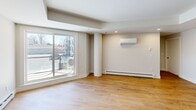 Located at 8 Walker Ave in Halifax, Nova Scotia, this well-appointed one-bedroom, one-bathroom unit offers a thoughtfully designed open-concept layout with modern finishes throughout. Light-toned hardwood flooring flows seamlessly across the entire space, creating a warm and cohesive aesthetic.

The combined kitchen and living area forms the heart of the unit. The kitchen is outfitted with sleek two-tone cabinetry in dark and white finishes, striking marble-look quartz countertops, a stainless steel undermount sink, and stainless steel appliances. Recessed lighting illuminates the space, while a tray ceiling detail in the living area adds architectural character. A sliding glass door opens onto a private balcony, and a wall-mounted mini-split unit provides additional climate control alongside baseboard heating.

The bedroom is a comfortable, well-proportioned room featuring large windows that frame views of the surrounding neighbourhood, a baseboard heater, and a built-in double closet with modern black hardware. The four-piece bathroom is finished with large-format white tile in the walk-in shower, a wood-toned vanity with a white countertop, and a full-width mirror. A dedicated laundry area with a stacked washer and dryer completes this practical and stylish unit.