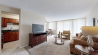 Located at 25151 Brookpark Rd in North Olmsted, Ohio, this single-floor residence offers a comfortable and well-organized layout designed for everyday living. The living room serves as the heart of the home, featuring plush wall-to-wall carpeting, a textured ceiling, and a generous bank of floor-to-ceiling windows dressed with vertical blinds that flood the space with natural light. A ceiling fan adds to the room's comfort, while the open flow connects seamlessly to a dedicated dining area, also benefiting from natural light through its own window. The kitchen is thoughtfully appointed with rich cherry wood cabinetry, dark granite countertops, stainless steel appliances including a range and built-in microwave, and durable tile flooring. The bedroom offers carpeted floors and an impressive amount of built-in closet space, with multiple bifold-door closets providing generous storage with shelving and hanging rods. A second bedroom or additional room also includes its own closet. The bathroom features white tile wainscoting, a warm wood vanity topped with a dark granite surface, and a large mirror with overhead lighting. Throughout, the neutral warm tones and consistent finishes create a cohesive and inviting atmosphere.