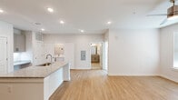 This thoughtfully designed single-floor residence offers a clean, modern aesthetic throughout its efficiently organized layout. The open-concept kitchen and living area serves as the heart of the home, anchored by a sleek kitchen island topped with granite countertops and an undermount sink. The kitchen is fully equipped with gray shaker-style cabinetry, stainless steel appliances including a range, microwave, and refrigerator, and matching granite counter surfaces — all set atop warm-toned light wood flooring that flows seamlessly through the main living areas. A dedicated laundry area is conveniently tucked nearby. The living room is bright and airy, featuring recessed lighting, a ceiling fan, and a glass door that invites natural light while providing outdoor access. The spacious bedroom is finished with plush carpet, a ceiling fan, and a window with outdoor views, offering a comfortable and restful retreat. An attached walk-in closet provides ample storage with wire shelving along multiple walls. The full bathroom features light tile flooring, a vanity with granite countertops, and a shower-tub combination with clean white tile surround. The overall ambiance is fresh, neutral, and move-in ready.