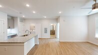 This thoughtfully designed single-floor residence offers a clean, modern aesthetic throughout its efficiently organized layout. The open-concept kitchen and living area serves as the heart of the home, anchored by a sleek kitchen island topped with granite countertops and an undermount sink. The kitchen is fully equipped with gray shaker-style cabinetry, stainless steel appliances including a range, microwave, and refrigerator, and matching granite counter surfaces — all set atop warm-toned light wood flooring that flows seamlessly through the main living areas. A dedicated laundry area is conveniently tucked nearby. The living room is bright and airy, featuring recessed lighting, a ceiling fan, and a glass door that invites natural light while providing outdoor access. The spacious bedroom is finished with plush carpet, a ceiling fan, and a window with outdoor views, offering a comfortable and restful retreat. An attached walk-in closet provides ample storage with wire shelving along multiple walls. The full bathroom features light tile flooring, a vanity with granite countertops, and a shower-tub combination with clean white tile surround. The overall ambiance is fresh, neutral, and move-in ready.