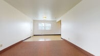 This single-floor space is designed with a practical, straightforward layout that maximizes functionality across its rooms. The expansive main living area is one of the most notable features, combining carpeted and hard-surface flooring zones that visually define distinct areas within the open space. White walls and flush-mount ceiling lighting keep the atmosphere clean and neutral throughout.

The kitchen is well-equipped, offering warm oak-toned cabinetry in both upper and lower configurations, providing ample storage. It includes a white electric range with overhead ventilation, a black dishwasher, a double-basin sink, and light-toned countertops. The flooring in the kitchen features a durable tile-style surface.

The bedrooms are carpeted in a warm earth tone, each with white walls and individual windows fitted with horizontal blinds, allowing natural light while maintaining privacy. Views from the windows include surrounding greenery and neighboring structures.

The full bathroom is clean and simply appointed, featuring a tub-shower combination, a white vanity with under-sink storage, a mirrored medicine cabinet, and tile-style flooring. Dark baseboards appear consistently throughout the unit, providing a subtle contrast to the light-colored walls and contributing to a cohesive interior aesthetic.