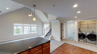 Located at Fairfield Broadway Knolls at Holbrook in Holbrook, NY, this two-floor residence offers a thoughtfully designed layout with a blend of comfort and functionality. The main level showcases a dramatic vaulted ceiling in the open-concept living and dining area, enhanced by recessed lighting and a ceiling fan. Natural light flows in through multiple windows, creating a bright and airy atmosphere. The kitchen is well-equipped with warm wood cabinetry, dark granite countertops, stainless steel appliances including a refrigerator, range, and microwave, and durable hardwood-style flooring. A kitchen island with matching cabinetry provides additional prep and storage space. A dedicated laundry area with side-by-side washer and dryer units, as well as a half bath featuring accessibility grab bars and tile flooring, round out the main level. The carpeted staircase leads to the upper floor, where a generously sized bedroom with crown molding, a ceiling fan, and plush carpet offers a comfortable retreat, complete with access to a walk-in closet. An additional versatile carpeted room with recessed lighting provides flexible living space. The full bathroom upstairs features a tub and shower combination with sliding glass doors and chrome fixtures, finished with clean tile work and crown molding accents.