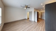 This well-appointed single-floor unit showcases a clean, modern design with consistent finishes carried throughout every room. The main living area is spacious and open, featuring light-toned luxury vinyl plank flooring, crisp white walls, and a ceiling fan with integrated lighting. Recessed lighting adds a polished touch, while a sliding barn door provides stylish access to an adjacent space. Natural light flows in through a large window fitted with blinds, enhancing the bright and airy ambiance of the space.

The kitchen is thoughtfully designed with rich, dark wood cabinetry contrasted by white quartz countertops and a classic subway tile backsplash. Stainless steel appliances — including a refrigerator, electric range, microwave, and dishwasher — complete the functional and contemporary culinary space. A double stainless steel sink with a modern faucet adds to the kitchen's practical appeal.

The bathroom offers a clean, accessible layout with large-format tile flooring, a spacious vanity featuring dark cabinetry and a white countertop, and a generously sized shower area equipped with a grab bar. Frosted glass door panels provide privacy while maintaining a sleek aesthetic. Overall, this unit presents a cohesive, move-in-ready space with modern design sensibilities throughout.