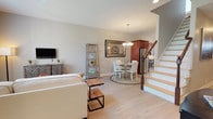 This two-story home is thoughtfully designed across two levels, offering a functional and comfortable layout. The main floor features an open-concept living and dining area with light hardwood-style flooring that runs throughout. The living room benefits from vaulted ceiling details and large windows that invite abundant natural light, creating a bright and airy atmosphere. A chandelier-lit dining area sits adjacent, providing a welcoming space for meals. The kitchen is well-appointed with rich cherry wood cabinetry, granite-style countertops, stainless steel appliances including a gas range, dishwasher, refrigerator, and microwave, as well as a pendant-lit window above the sink. An attached garage with an automatic opener provides direct interior access and ample storage potential. Upstairs, the open loft area serves as a versatile secondary living or workspace, featuring plush carpeting, a ceiling fan, and a window with views of the surrounding neighborhood. The bedroom is generously sized with soft carpeting, a ceiling fan, closet, and a large window. The full bathroom features tile flooring, white cabinetry with dark countertops, and a spacious vanity.