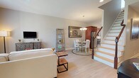 This two-story home is thoughtfully designed across two levels, offering a functional and comfortable layout. The main floor features an open-concept living and dining area with light hardwood-style flooring that runs throughout. The living room benefits from vaulted ceiling details and large windows that invite abundant natural light, creating a bright and airy atmosphere. A chandelier-lit dining area sits adjacent, providing a welcoming space for meals. The kitchen is well-appointed with rich cherry wood cabinetry, granite-style countertops, stainless steel appliances including a gas range, dishwasher, refrigerator, and microwave, as well as a pendant-lit window above the sink. An attached garage with an automatic opener provides direct interior access and ample storage potential. Upstairs, the open loft area serves as a versatile secondary living or workspace, featuring plush carpeting, a ceiling fan, and a window with views of the surrounding neighborhood. The bedroom is generously sized with soft carpeting, a ceiling fan, closet, and a large window. The full bathroom features tile flooring, white cabinetry with dark countertops, and a spacious vanity.