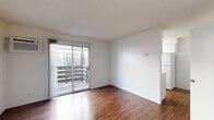 Located at 2751 Monument Blvd in Concord, CA, this one-bedroom, one-bathroom unit offers a practical and well-organized single-floor layout. Rich hardwood-style flooring runs throughout the entire space, providing a warm, cohesive aesthetic in every room.

The living room is a bright, open area featuring sliding glass doors that lead to a private balcony, allowing natural light to fill the space. A wall-mounted air conditioning unit ensures year-round comfort. The clean white walls and textured ceiling complete the room's simple, functional design.

The kitchen is laid out in a galley style, featuring white cabinetry, light stone-patterned countertops, a full-size refrigerator, and an electric range. A window above the sink brings in additional natural light, keeping the space bright and airy.

The bedroom is a well-proportioned room with a window overlooking the exterior and a full-width sliding-door closet offering ample storage. A hallway connects the main living areas and provides access to the bathroom, which is equipped with a single-sink vanity with stone-patterned countertop, a full tub and shower combination with grab bars, and matching hardwood-style flooring. The unit's straightforward layout makes efficient use of every square foot.
