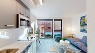Located in Portland's sought-after Pearl District, Unit 306 at 1315 NW Johnson Street is a thoughtfully designed studio that maximizes every inch of its open-concept layout. The space is anchored by dramatic floor-to-ceiling windows that flood the interior with natural light and frame views of the surrounding urban streetscape, including the neighborhood's iconic brick architecture.

The kitchen runs along one wall and features dark upper cabinetry, light lower cabinetry, stainless steel appliances including a refrigerator and microwave, a single-basin sink, and clean white countertops with a tile backsplash. A compact dining area with a round wooden table sits adjacent to the windows, creating an ideal spot for casual meals with a city view.

The living area is open and airy, with light wood-look flooring that extends throughout the entire unit, contributing to a cohesive and modern aesthetic. A dedicated vanity nook with a round mirror and built-in lighting offers a functional workspace or grooming station.

The bathroom is clean and efficiently designed, featuring a glass-enclosed shower, a wall-mounted vanity with white countertop and dark cabinetry, and a stacked in-unit washer and dryer — a notable convenience. The overall ambiance is bright, minimalist, and urban, with a neutral palette that complements the modern architecture of this well-appointed Pearl District residence.