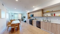 Located in the Mar Vista neighborhood of Los Angeles, this modern single-floor residence offers a thoughtfully designed open-concept layout with clean lines and a warm, neutral palette throughout. Light oak hardwood flooring flows seamlessly across the living, dining, and kitchen areas, creating a cohesive and airy atmosphere.

The kitchen is a standout feature, outfitted with flat-front wood-tone cabinetry, open shelving, light quartz countertops, and a full suite of stainless steel appliances including a gas range, dishwasher, and French door refrigerator. The dining area sits adjacent to the kitchen and features a solid wood table, lending a natural, organic feel to the space.

The living room is bright and inviting, anchored by a large sliding glass door that opens to a private balcony, filling the room with natural light and offering outdoor views. Two bedrooms provide comfortable accommodations; one bedroom also benefits from direct balcony access and a built-in wood-tone wardrobe. Both bathrooms are finished in contemporary style — one with large-format grey tiles, a glass-enclosed walk-in shower, and a wall-mounted sink, and the other with a glass shower enclosure, wood vanity, and open shelving. Recessed lighting throughout adds a polished, modern touch to every room.