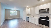 Located at 1720 Crestdale Dr in Houston, TX, this 1-bedroom, 1-bathroom unit offers a thoughtfully designed single-floor layout with modern finishes throughout. Light wood-style laminate flooring flows seamlessly across all main living areas, creating a cohesive and contemporary feel.

The open kitchen and living area serves as the heart of the unit. The kitchen is outfitted with white shaker-style cabinetry, light countertops, and a full suite of stainless steel appliances including a refrigerator, electric range, built-in microwave, and dishwasher. Recessed lighting and a neutral color palette keep the space feeling bright and clean.

The bedroom is a comfortable, well-proportioned room featuring a ceiling fan, a window with outdoor views that allow natural light to fill the space, and access to a dedicated closet. The neutral warm-toned walls complement the wood-style flooring for a calm, inviting atmosphere.

The bathroom is finished with large-format marble-look ceramic tile on both the floors and the tub surround, lending an elegant touch. The soaking tub with shower combination is complemented by brushed nickel fixtures and a clean white vanity.

Overall, the unit presents a clean, modern aesthetic with consistent finishes and a practical, well-organized layout.