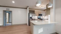 Located on Deer Drive in the desirable Lakewood Ranch community of Florida, this single-floor residence offers a thoughtfully designed open-concept layout with modern finishes throughout. Light wood-look flooring flows seamlessly across the main living areas, complemented by crisp white walls and warm taupe crown molding that adds an elegant architectural touch.

The kitchen serves as a central highlight, boasting light wood cabinetry, a striking built-in wine rack, stainless steel appliances — including a French door refrigerator, range, and microwave — and a generous island with a bright white countertop and undermount sink. Pendant lighting and track lighting illuminate the space, while a large window allows natural light to pour in.

The living and dining areas are open and airy, offering generous room to arrange and personalize. Bedrooms feature soft wall-to-wall carpeting for comfort, with louvered and paneled interior doors adding character. A dedicated laundry closet with a louvered door provides convenient in-unit utility access.

Two bathrooms round out the home, each featuring light wood vanities with white countertops, modern chrome hardware, and wood-look tile flooring. The primary bath includes a glass-enclosed walk-in shower with marble-style tile, while the secondary bath offers a clean, functional layout with ample storage.
