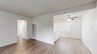 Located at 11950 Old River School Rd in Downey, CA, this single-floor 2-bedroom, 2-bathroom unit offers a practical and well-organized layout. The living room features wood-style laminate flooring, a textured ceiling, a wall-mounted A/C unit, and large windows with vertical blinds that bring in natural light and outdoor views. It flows into a dedicated dining area and a functional kitchen equipped with white cabinetry, a granite-style peninsula countertop, tile backsplash, a gas range, and tile flooring. Both bedrooms are carpeted and include ceiling fans with light fixtures and windows with vertical blinds. The primary bedroom offers a comfortable, well-proportioned retreat, while the second bedroom features a sliding closet. The unit includes three closets in total, providing ample storage throughout. Both bathrooms are finished in white with vanities, tile flooring, and bright overhead lighting. One bathroom includes a shower/tub combo. A central hallway connects the bedrooms and bathrooms, contributing to an efficient and navigable floor plan. The overall aesthetic is clean and neutral, with white walls throughout creating a bright, move-in ready atmosphere.