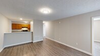 Located at 3105 Wrightsboro Rd in Augusta, Georgia, this single-story, 4-bedroom, 3-bathroom home offers a practical and well-organized layout. The open living room flows seamlessly into the kitchen, which is separated by a half-wall counter. The kitchen features warm honey-toned wood cabinetry, dark granite-style countertops, black appliances including a range and refrigerator, and ample storage with both upper and lower cabinets. Wood-look vinyl plank flooring runs throughout the home, providing a cohesive and easy-to-maintain surface. Neutral warm-gray walls and textured ceilings are consistent across all rooms, lending a clean and uniform aesthetic. The four bedrooms are modestly sized, with the primary bedroom offering a compact yet functional footprint. Each room includes ceiling-mounted light fixtures and closet access. The three bathrooms are straightforward in design, featuring white tub-shower combos with chrome fixtures and vanities with large mirrors and white countertops. A central hallway connects the bedrooms and bathrooms efficiently. The home's simple, no-frills design makes it a practical residential space, ideal for everyday living in the Augusta area.