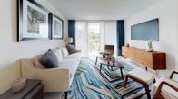Unit 51-308 is a thoughtfully appointed single-floor residence that balances contemporary style with everyday comfort. The living area serves as the centerpiece of the home, featuring large sliding glass doors dressed in elegant teal drapes that flood the space with natural light and offer views of the outdoors. A vibrant blue-toned area rug anchors the seating arrangement, complemented by mid-century modern furnishings including a wooden credenza and an accent chair, creating a warm and inviting atmosphere. A wall-mounted television adds a practical touch to this well-curated space.

The kitchen is efficiently laid out with light wood countertops, white cabinetry, and tile flooring. It is fully equipped with stainless steel appliances including an electric range, a built-in dishwasher, and a microwave, making it well-suited for everyday meal preparation.

The bedroom is a tranquil retreat, highlighted by a striking blue upholstered panel headboard and crisp white bedding. Light hardwood flooring, warm bedside lighting, and mid-century style nightstands contribute to the room's calm and restful character.

The bathroom is clean and functional, finished with tile flooring, a white vanity with an integrated sink, and a shower-tub combination, providing all essential amenities in a tidy, well-maintained space.