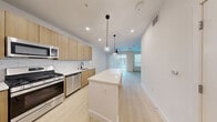 Located at 3930 Paradise Rd in Las Vegas, NV, this thoughtfully designed single-floor unit offers a clean, modern aesthetic throughout. Light-toned luxury vinyl plank flooring runs continuously across the entire space, creating a seamless and cohesive feel.

The kitchen is a standout feature, outfitted with flat-front wood-grain cabinetry, a white quartz island with pendant globe lighting overhead, stainless steel appliances including a gas range, dishwasher, built-in microwave, and a French door refrigerator. A subway-style tile backsplash and matte black fixtures add refined contrast to the warm cabinetry tones.

The open living area flows naturally from the kitchen and is bathed in natural light from a large sliding glass door dressed with vertical blinds, complemented by an additional window. A ceiling fan with integrated lighting provides both comfort and function.

The bathroom is sleek and well-appointed, featuring a floating wood-tone vanity with an illuminated mirror, a soaking tub with a glass panel enclosure, and clean white finishes throughout. Direct access to a dedicated closet with built-in shelving provides excellent organization.

The overall ambiance is bright, airy, and contemporary — an efficient and stylish space well-suited for modern urban living in the heart of Las Vegas.