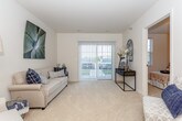 This single-floor residence offers a well-organized layout that efficiently connects the main living areas. The kitchen is a functional highlight, outfitted with rich medium-toned wood cabinetry, granite-style countertops, and a full suite of stainless steel appliances, including a refrigerator, range, microwave, and dishwasher. The tile flooring and ample upper and lower cabinet storage contribute to both practicality and visual warmth. A peninsula with seating connects the kitchen directly to the dining area, which accommodates a round table and chairs beneath a pendant light fixture. The entry door opens into this dining space, which features plush carpeting that continues throughout the rest of the unit.

The primary bedroom is generously sized with natural light from a window, carpeted flooring, and access to a closet. The second bedroom, similarly carpeted and windowed, includes a reach-in closet and offers a comfortable, well-proportioned layout. The bathroom features stone-look tile flooring, a vanity with wood cabinetry, a walk-in shower with a glass enclosure, grab bars for accessibility, and a stacked washer and dryer unit conveniently located within the same space. The overall ambiance is calm and neutral throughout.