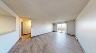 Located at 1251 S Bellaire St in Glendale, Colorado, this 2-bedroom, 1-bathroom residence offers a practical and well-organized layout across a single floor. Light wood-style flooring runs throughout the unit, complementing the neutral color palette and textured ceilings found in each room.

The open living room is bright and spacious, featuring a wall-mounted air conditioning unit and a sliding glass door that invites natural light and provides access to an outdoor area. Baseboard heating is present throughout the home, ensuring year-round comfort.

The kitchen is thoughtfully designed with a two-tone cabinet scheme — dark lower cabinets paired with crisp white upper cabinets — and granite-style countertops. It includes a full suite of appliances: a refrigerator, electric range, and dishwasher, along with a skylight-style ceiling fixture that enhances the workspace.

Both bedrooms feature the same warm wood-style flooring and natural light from large windows. The primary bedroom is generously sized and notably includes dual closets with bi-fold doors, offering ample storage. The second bedroom also features a window with outside views and its own closet.

The bathroom includes a full tub-shower combination with clean white tile surround. A hallway connects the main living areas to the bedrooms and bathroom, maintaining a functional flow throughout the home.