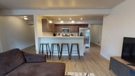 Located at 1608 East South Riverton Avenue in Spokane, WA, this well-appointed single-floor unit offers a thoughtfully designed layout with modern finishes throughout. The open-concept living and kitchen area serves as the heart of the home, where a spacious kitchen features dark espresso cabinetry, stainless steel appliances including a French door refrigerator, electric range, and microwave, all complemented by light quartz countertops and a large peninsula with bar seating for four. Pendant lighting adds a polished touch above the peninsula, while recessed lighting illuminates the kitchen workspace. Light wood-style flooring flows throughout the main living areas, creating a cohesive and bright atmosphere. The living room offers generous space with a window that brings in natural light and outdoor views of the surrounding greenery. The primary bedroom is carpeted and features a window, access to a walk-in closet, and an en-suite bathroom with a wide vanity, dark cabinetry, and a separate shower. A second bedroom is equally comfortable with carpet, a large window with outdoor views, and ample space. A second bathroom includes a vanity with dark cabinetry, a tub/shower combination, and light wood-style flooring, completing this well-rounded and functional home.