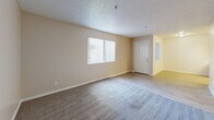 Located at 8605 N 59th Ave in Glendale, Arizona, this two-bedroom, two-bathroom unit offers a practical single-floor layout designed for comfortable everyday living. The combined kitchen and living room serves as the heart of the home, with the living area featuring neutral-toned carpet, light-wood-style flooring at the entry, and a window with vertical blinds that brings in natural light. The kitchen is laid out in a galley style, lined on both sides with warm wood cabinetry, white countertops, and white appliances, including a range and refrigerator. A skylight above the kitchen adds an extra source of natural illumination. Both bedrooms are carpeted and feature sliding-door closets for storage, with windows allowing natural light to filter in. The primary bedroom is a well-proportioned space with direct access to a hallway. The two bathrooms offer distinct configurations — one includes a soaking tub and wood-toned vanity cabinetry with light wood-style flooring, while the second features a walk-in shower with tiled surround and built-in shelving. Textured ceilings are consistent throughout the unit, and the overall color palette of soft whites and warm beiges creates a clean, neutral ambiance throughout.
