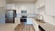 Located at 4040 Shopton Rd in Charlotte, NC, this single-floor residence offers a thoughtfully designed layout with a clean, contemporary aesthetic throughout. The open living area features wood-look plank flooring and track lighting, creating a bright and versatile space with access to additional rooms via a central corridor.

The kitchen is a standout feature, equipped with white shaker-style cabinetry extending to the ceiling, granite countertops, a subway tile backsplash, and a full suite of stainless steel appliances including a refrigerator, range, microwave, and dishwasher. A hallway off the kitchen leads to the unit's entry and provides additional storage access.

The bedrooms are carpeted and filled with natural light from large windows with blinds. At least one bedroom includes a walk-in closet with built-in shelving, offering practical storage. Additional bedrooms are well-proportioned with neutral finishes.

The bathrooms are finished with granite-topped vanities and wood-look flooring. One bathroom features a soaking tub with white subway tile surround and a curved shower rod, while another offers a standalone walk-in shower with a framed glass door and a single-sink vanity.