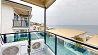 Located on Coastline Drive in Malibu, California, this well-designed 2-bedroom, 4-bathroom residence offers an impressive coastal lifestyle with direct views of the Pacific Ocean and sandy beach from a private glass-railed balcony. The single-floor layout makes efficient use of its space, connecting the main living areas with a clean, modern flow. The kitchen is outfitted with rich cherry wood cabinetry, granite countertops, a mosaic tile backsplash, and a full suite of stainless steel appliances including a refrigerator with ice maker, range, microwave, and dishwasher — all accessible via a convenient breakfast bar pass-through. Hardwood flooring runs through the main areas, while soft carpeting provides comfort in the bedrooms. The spacious primary bedroom features its own en-suite access and generous natural light. The bathrooms are well-finished, with granite vanity countertops, wood cabinetry, and at least one bathroom showcasing a floor-to-ceiling travertine tile walk-in shower with glass enclosure. A dedicated laundry area houses a full-size side-by-side washer and dryer with overhead cabinetry. The balcony provides expansive, unobstructed views of the coastline — a standout feature that captures the essence of Malibu beachside living.