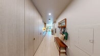 Located at 700 Broadway in Santa Monica, CA, this thoughtfully designed studio offers an efficient and stylish single-floor layout. The entry corridor makes excellent use of space with floor-to-ceiling cabinetry in a warm wood finish, light hardwood flooring underfoot, and a built-in bench with a wall-mounted mirror — creating a functional and welcoming entryway. The galley-style kitchen flows seamlessly along the corridor, featuring sleek cabinetry and integrated appliances. The open living area is bright and airy, benefiting from a large window that frames views of the surrounding Santa Monica streetscape and invites generous natural light. The space comfortably accommodates both a sleeping area and a living room setup, with a neutral warm palette throughout. The bathroom is a standout feature, finished with floor-to-ceiling marble-style tile, a glass-enclosed combination soaking tub and shower, a floating wood vanity with stone countertop, and a large mirror with warm accent lighting — delivering a spa-like experience. A dedicated closet and in-unit laundry add practical convenience. Overall, the space strikes a balance between compact urban living and refined, modern finishes.